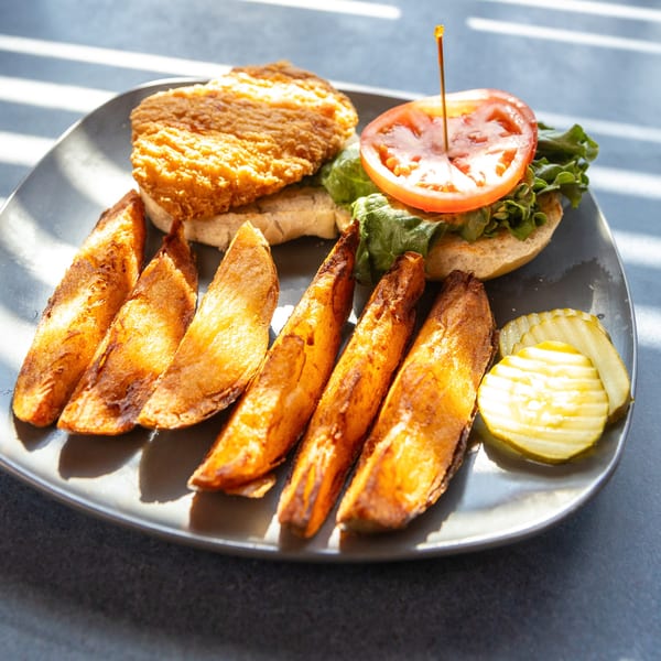 Ollie's Restaurant's crispy fried chicken sandwich with lettuce, tomato, steak fries, and pickles.