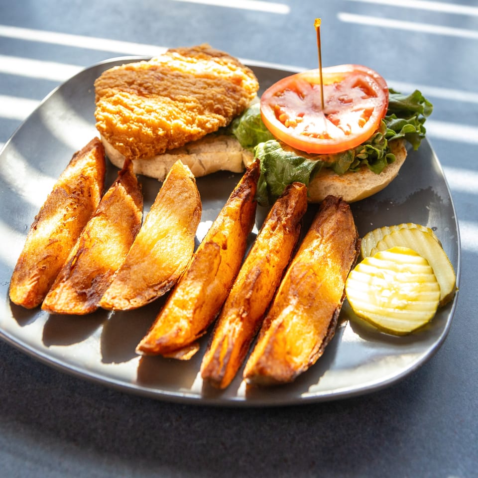Ollie's Restaurant's crispy fried chicken sandwich with lettuce, tomato, steak fries, and pickles.