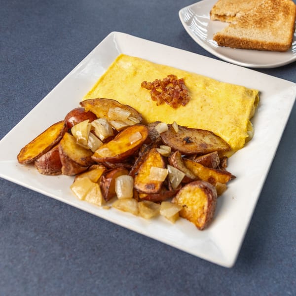 Ollie's Restaurant's American breakfast: omelet with caramelized onions, roasted potatoes, and toast.