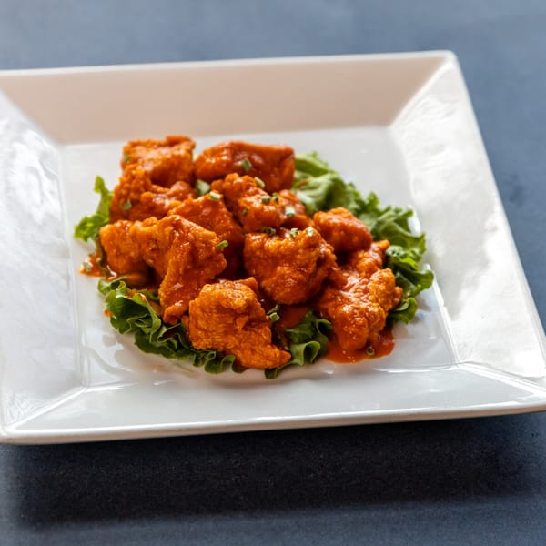 Ollie's Restaurant's American cuisine features crispy orange chicken bites on a bed of fresh green lettuce.